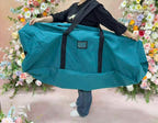Person carrying a teal flower wall storage bag with black shoulder straps
